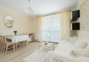 A room with a dining area, a sofa, and a large window with curtains. - Dunikowskiego Cosy Apartment (Szczecin)