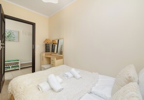 Een hotelkamer met een bed, nachtkastje, spiegel en kledingkast.