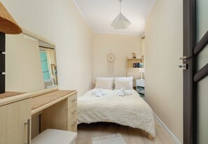A bedroom with a bed, a bedside table, a mirror, a dreamcatcher, and a shelf with books. - Dunikowskiego Cosy Apartment (Szczecin)