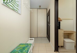 A narrow hallway with a bed, a wardrobe, and a desk area. - Dunikowskiego Cosy Apartment (Szczecin)