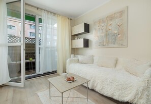 A modern living room with a sofa, a coffee table, and a painting on the wall. - Dunikowskiego Cosy Apartment (Szczecin)