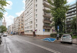 A multi-story residential building with balconies, a parking sign, and a pedestrian crossing. - Złota Spacious Apartment (Warszawa)