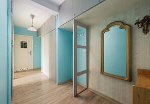 A hallway with a wooden floor, a white door, and a blue wall with a decorative mirror. - Złota Spacious Apartment (Warszawa)