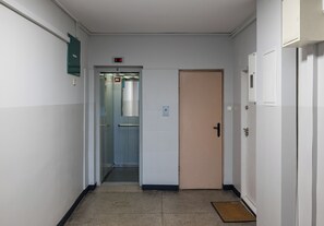 A narrow hallway with a door on the right and an elevator on the left. - Złota Spacious Apartment (Warszawa)
