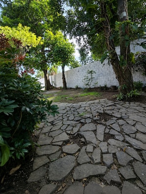A paved courtyard with a white brick wall and trees.