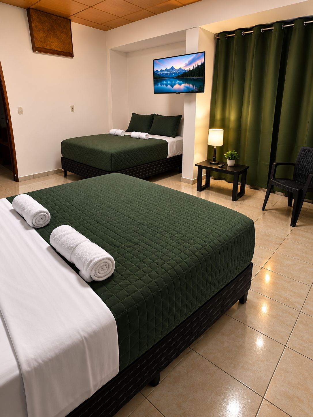 A hotel room with two beds, a TV, a lamp, a chair, and a view of mountains.