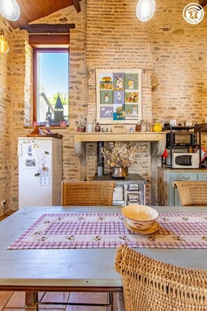 Cuina rústica amb paret de maó, sostre de fusta i finestra amb vista a una torre.