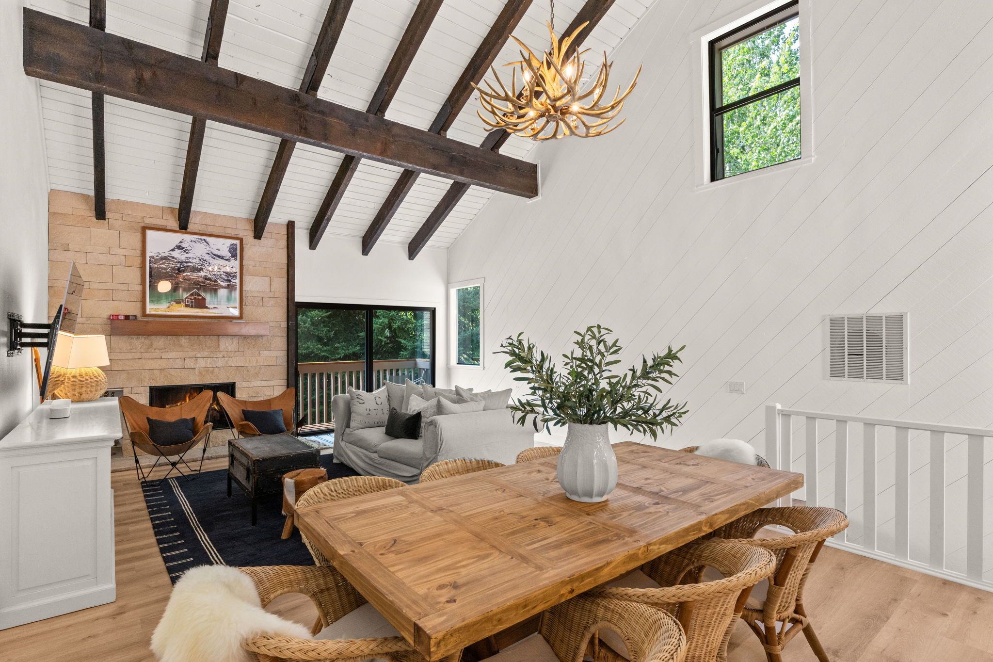 A spacious room with a wooden dining table, wicker chairs, a sofa, and a fireplace.