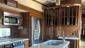 Una cocina moderna con una isla central, electrodomésticos de acero inoxidable, armarios de madera e iluminación colgante.