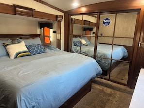 A bedroom with two beds, a wardrobe, and a mirror. - Spacious, fully stocked RV in quiet, peaceful Lynndyl (Lynndyl)
