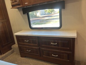 A kitchenette with a window, a countertop, and wooden cabinets.