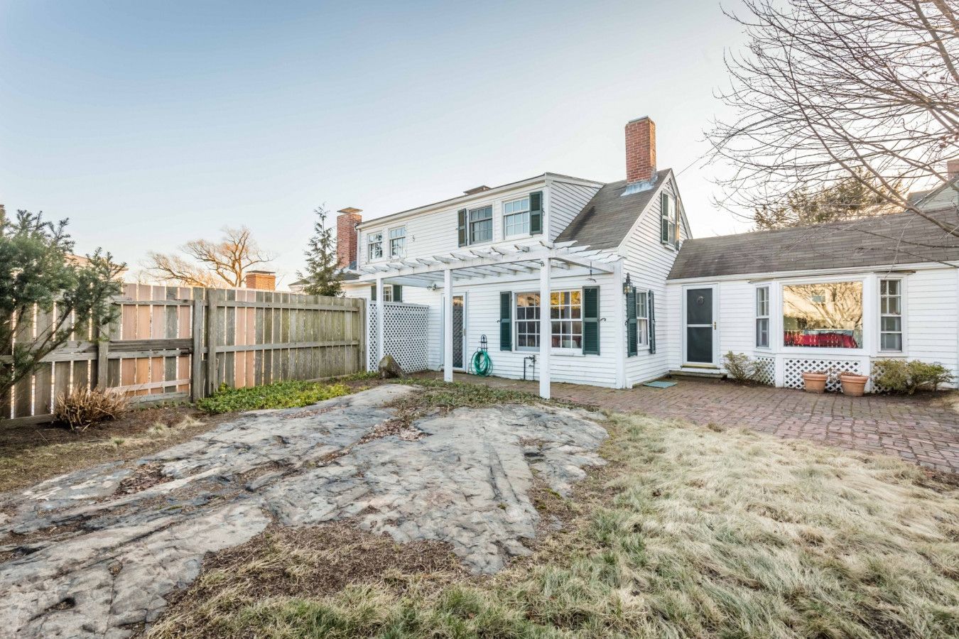 Une maison à deux étages avec un patio couvert et une cour arrière clôturée.