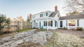 Une maison à deux étages avec un patio couvert et une cour arrière clôturée.