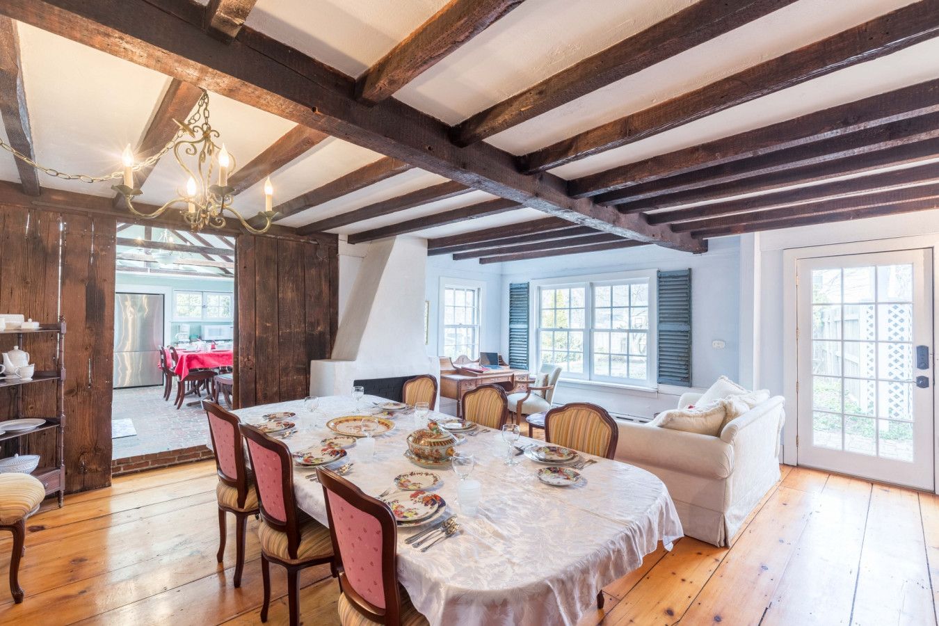 Une salle à manger avec un plafond en bois, un lustre et une table dressée pour le repas.