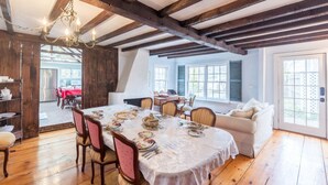 En spisestue med træloft, en lysekrone og et bord dækket til et måltid.