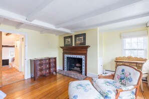 Una sala de estar con chimenea, muebles de madera y un sofá estampado con motivos florales.