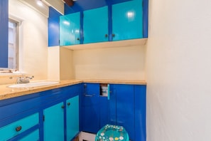 Een badkamer met een wastafel, spiegel en blauwe kastjes.