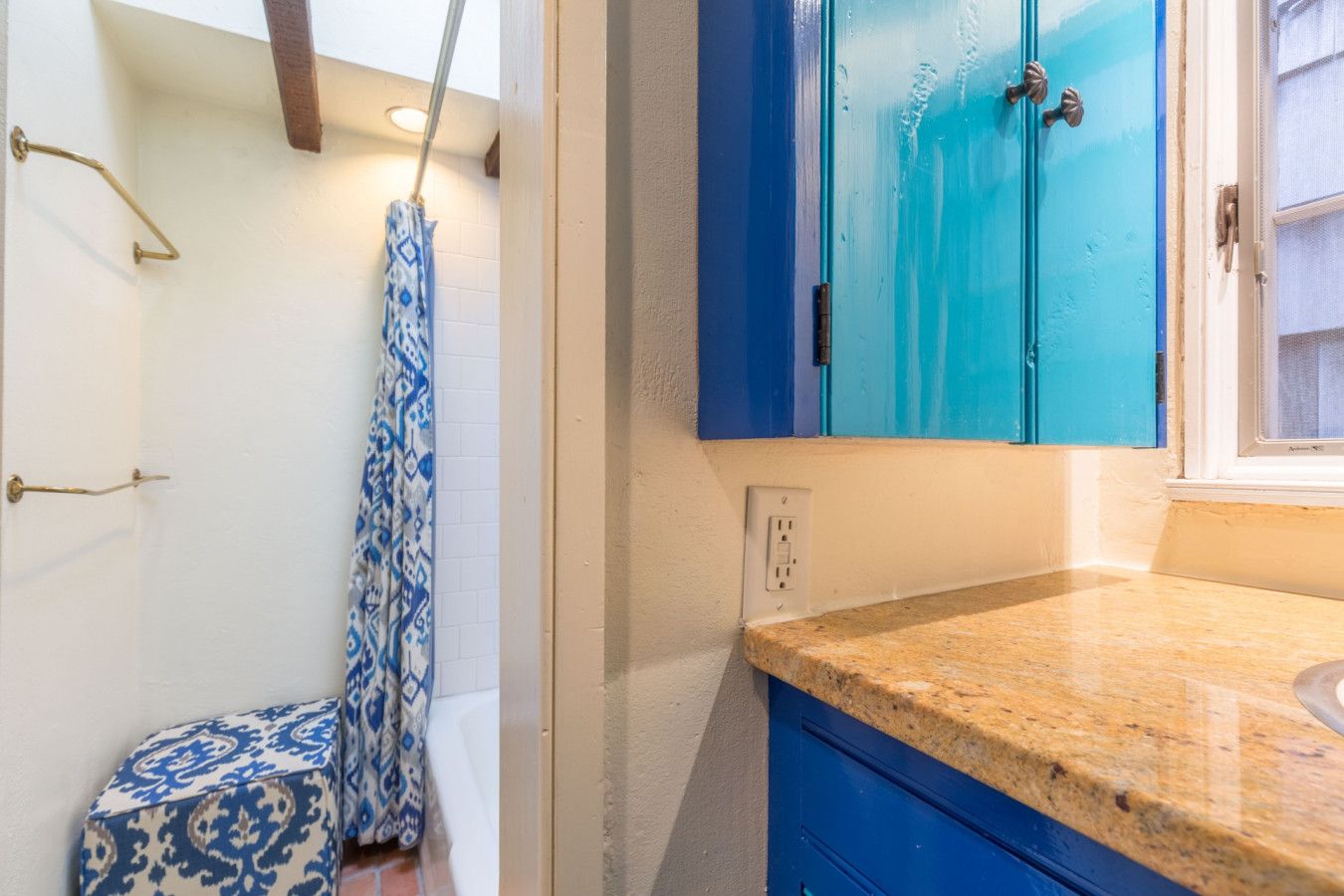 A bathroom with a shower, a sink, and blue cabinets.