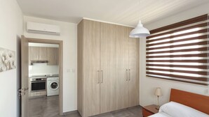 Quarto com cama, guarda-roupa, luminária pendente e janela com persianas.