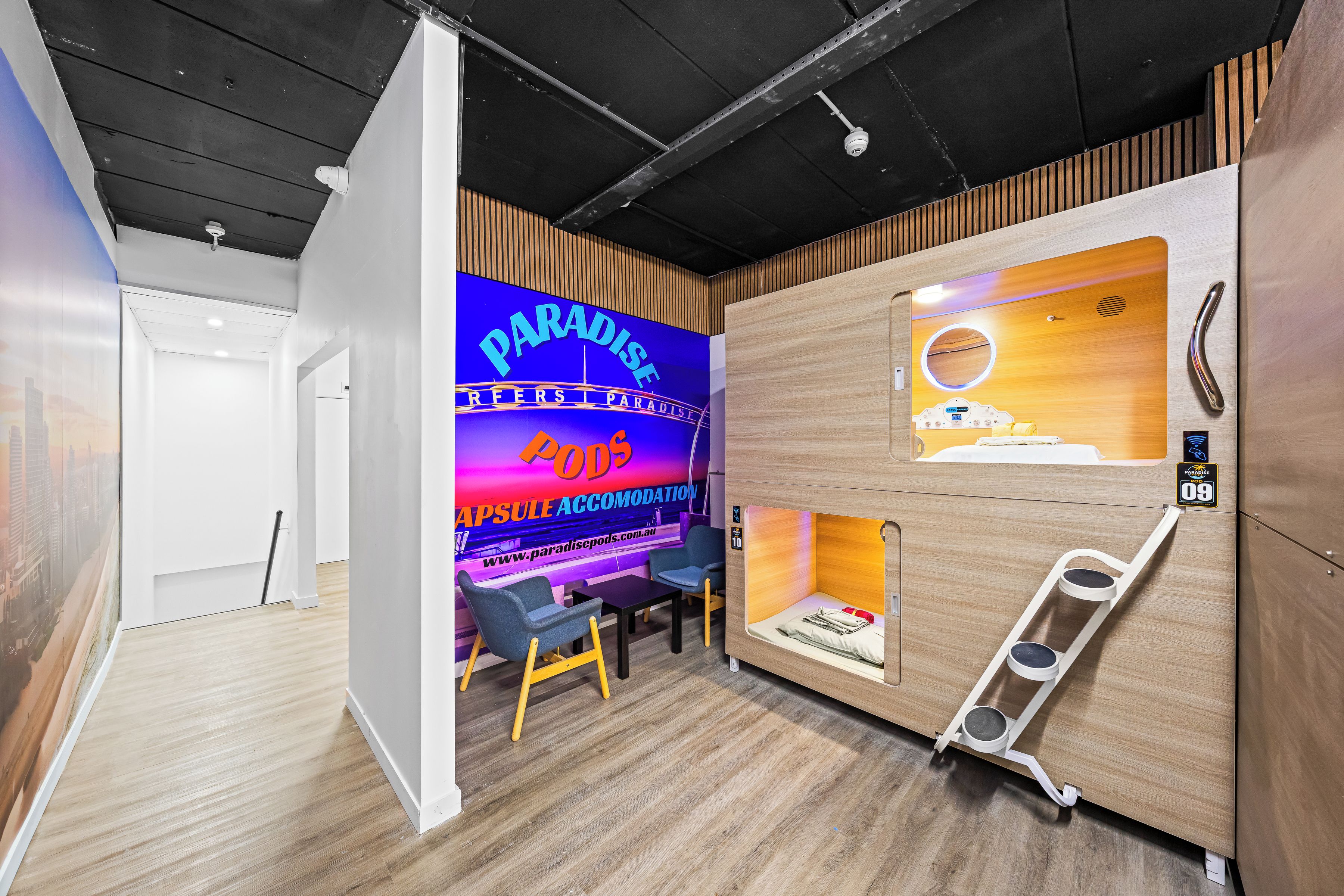 A modern interior with a wooden wall, a neon sign, a desk, chairs, and a ladder.
