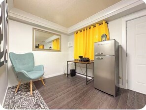 A compact kitchen with a refrigerator, a chair, and a dining table.
