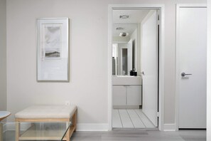 A minimalist bathroom with a white sink, mirror, and a door leading to another room. - Lakeview CityPlace 2BR | Free Parking & Balcony | Parking Available (Toronto)