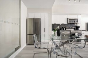 A modern kitchen with stainless steel appliances, a glass dining table, and clear chairs. - Lakeview CityPlace 2BR | Free Parking & Balcony | Parking Available (Toronto)