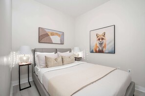 A bedroom with a bed, two bedside tables, a lamp, and two framed pictures on the wall. - Lakeview CityPlace 2BR | Free Parking & Balcony | Parking Available (Toronto)