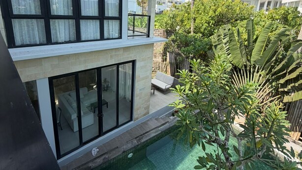 Un bâtiment moderne à deux étages, doté d’une piscine, d’un espace extérieur aménagé et d’une végétation luxuriante.