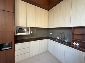 A compact kitchen with a microwave, sink, and wooden cabinets. - Araya Villa Cemagi 8 (Cemagi)