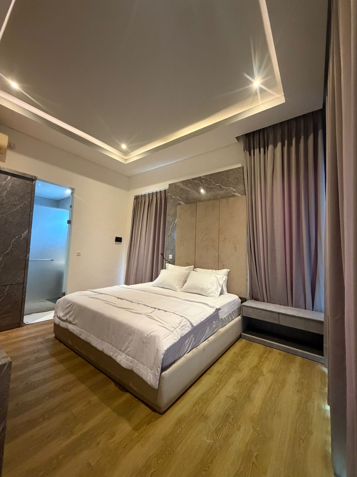 Un dormitorio moderno con una cama grande, un banco empotrado y vistas al exterior.