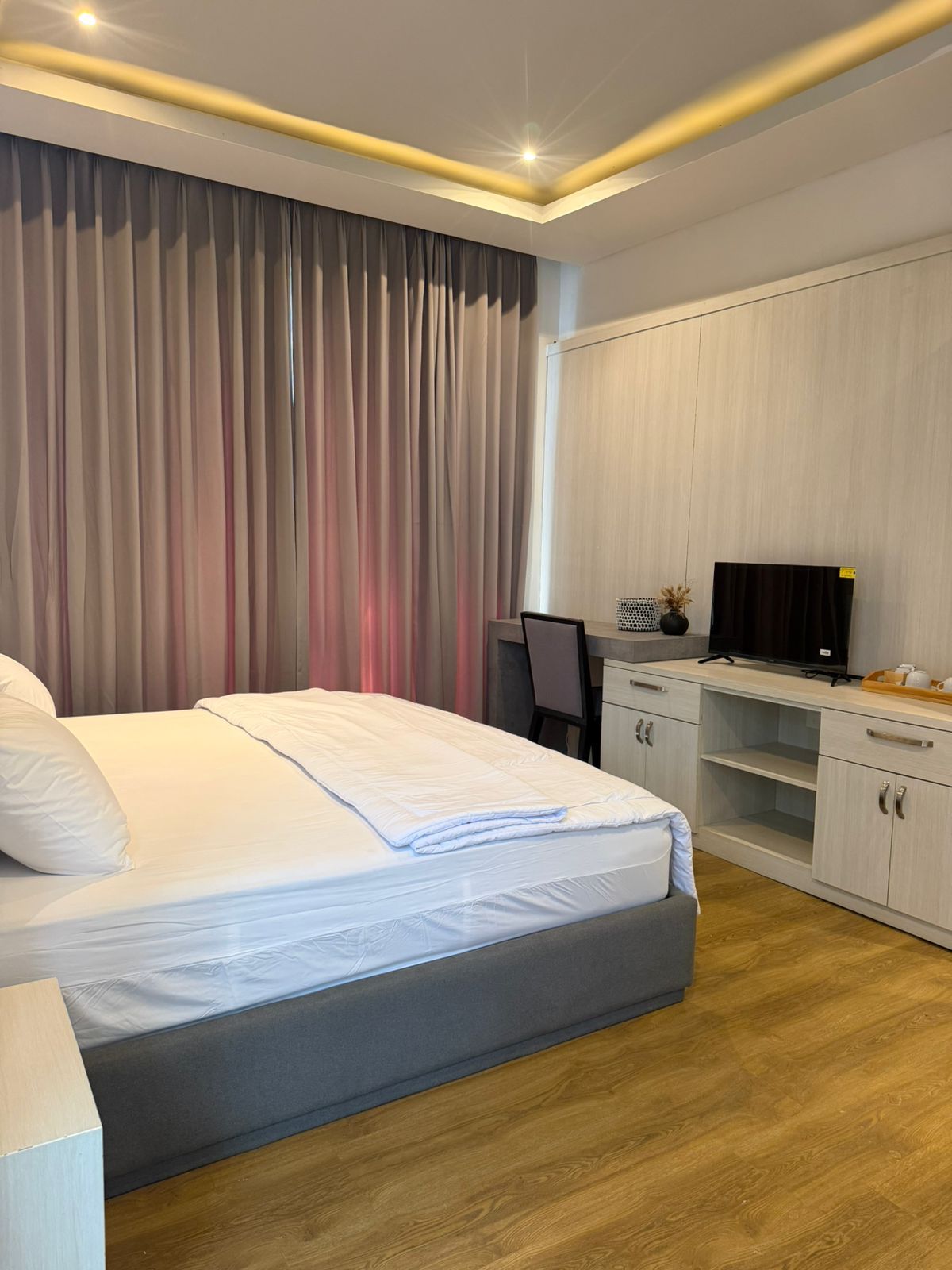 A hotel room with a bed, a desk, a television, and a wardrobe.