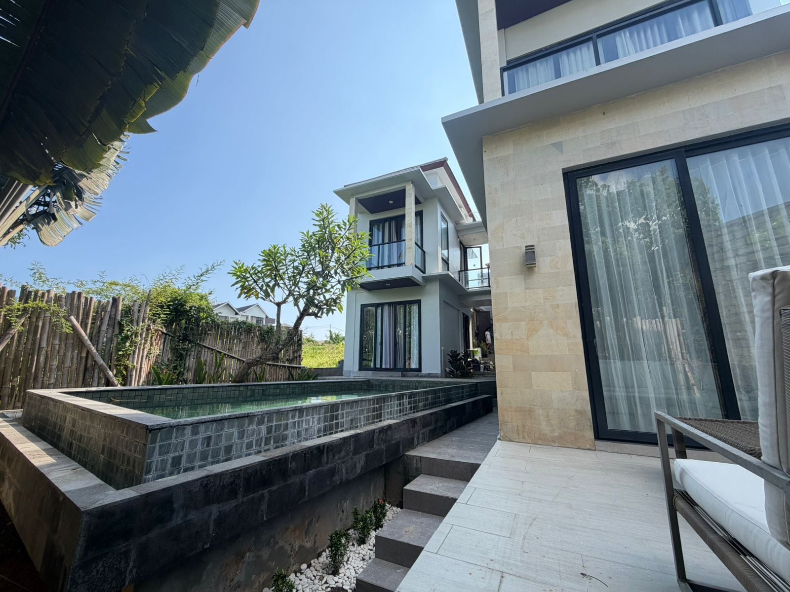Una casa moderna de dos pisos con piscina, un patio cubierto y vistas del entorno.