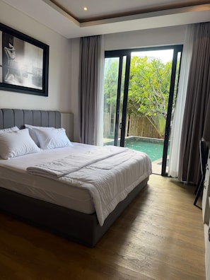 Un dormitorio con una cama grande, una puerta corrediza de vidrio que da a una piscina y un cuadro en la pared.