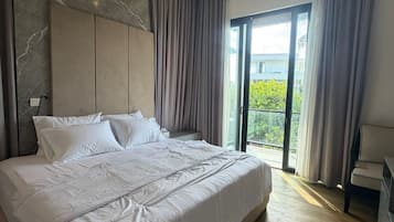 Un dormitorio moderno con una cama grande, cabecera y vistas al exterior a través de un ventanal.