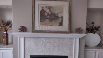 A fireplace with a framed painting above it, flanked by decorative vases.