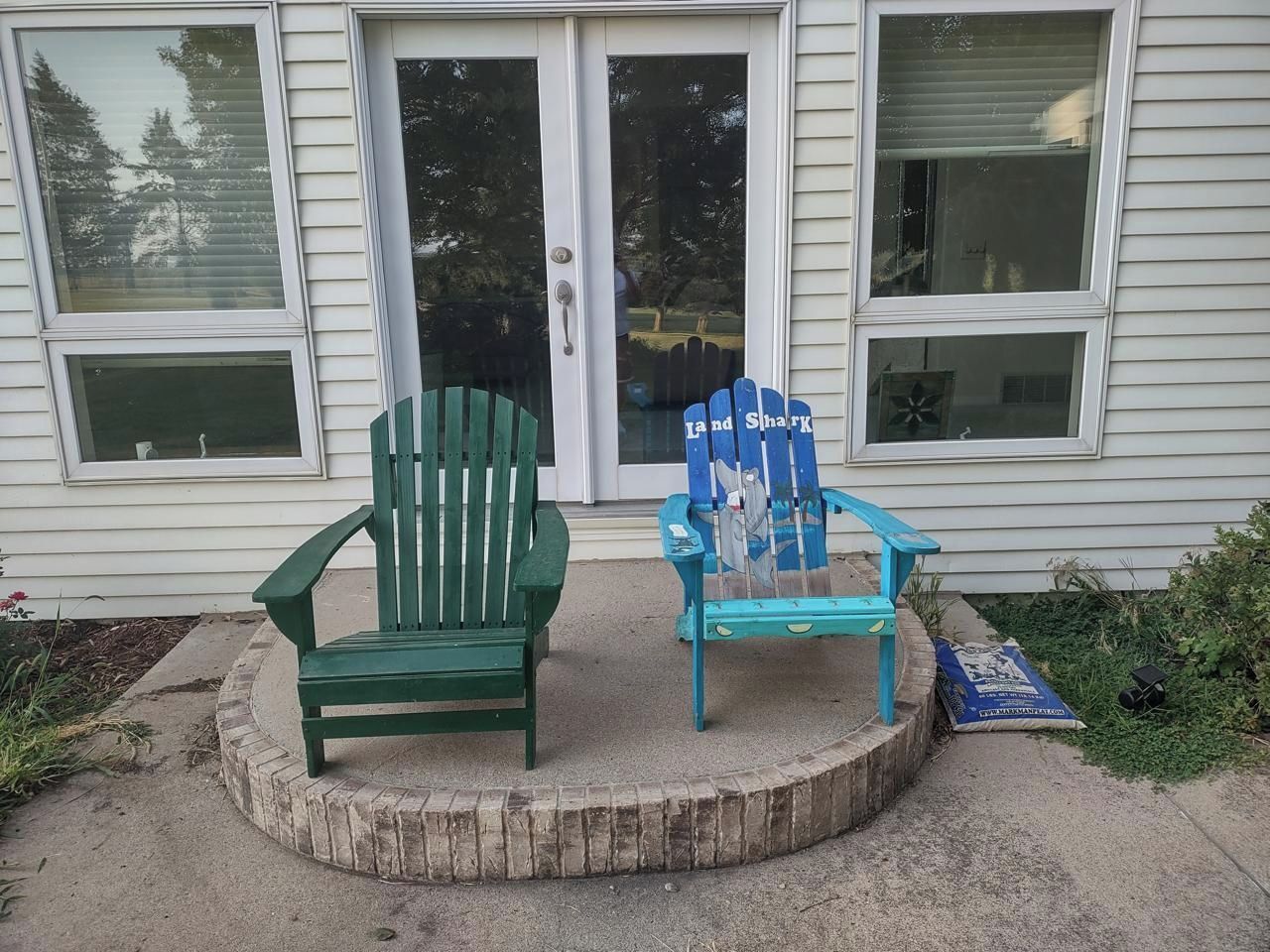 Deux fauteuils Adirondack sont placés devant une maison, devant la porte d’entrée et les fenêtres.