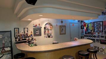 A bar area with a curved counter, stools, and various decorations including framed pictures and bottles.