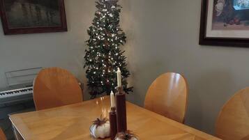 Een eettafel met stoelen, een kerstboom en kaarsen.