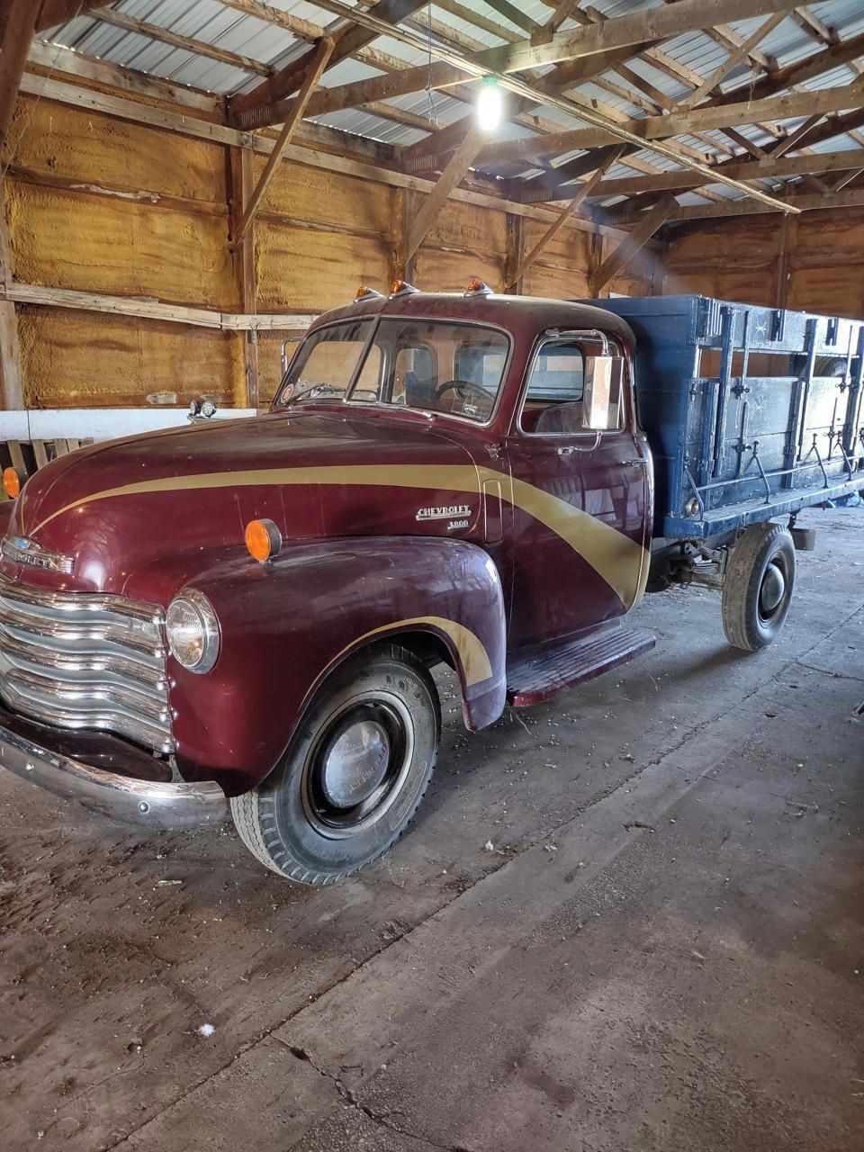 Ein alter Chevrolet-Truck steht in einer Scheune mit Holzwänden und einem Metalldach.