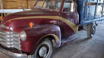 Ein alter Chevrolet-Truck steht in einer Scheune mit Holzwänden und einem Metalldach.