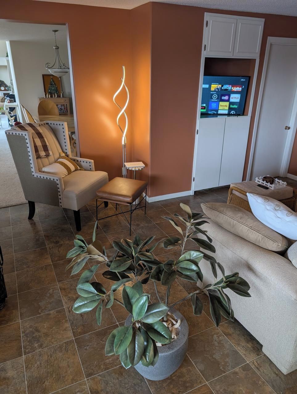 A living room with a sofa, armchair, and a potted plant.