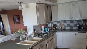 A kitchen with white cabinets, a stainless steel dishwasher, a tiled backsplash, and a red rug. - Bed and Breakfast • King Bed + Game Room + Fire Pit (Kiron)