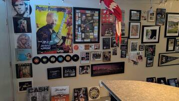Una pared decorada con carteles enmarcados, fotografías y discos de vinilo, con un loro colgando del techo.