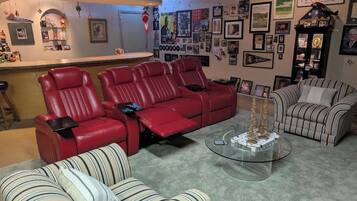 A living room with a red sofa set, a striped sofa, and a glass coffee table.