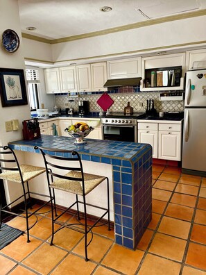 A kitchen with white cabinets, a tiled island, and a stove.