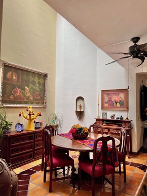 A dining area with a round table, red upholstered chairs, a decorative centerpiece, and a ceiling fan.