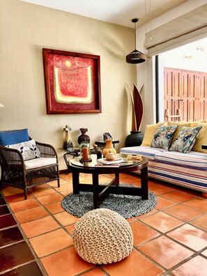 A living room with a sofa, a coffee table, a chair, a rug, and a painting on the wall.
