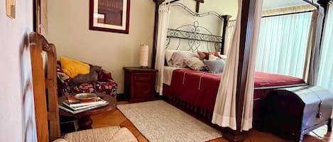 Ein Schlafzimmer mit einem Himmelbett, einem Holzstuhl, einem Nachttisch und einem Deckenventilator.