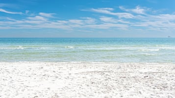 Ein Strand mit blauem Himmel und ruhigem Wasser.